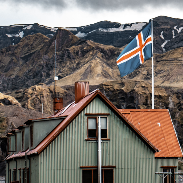 Iceland flag on top of a house with mountains in background