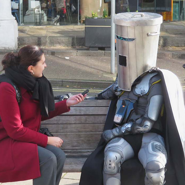Count Binface sat on a bench chatting to a female interviewer