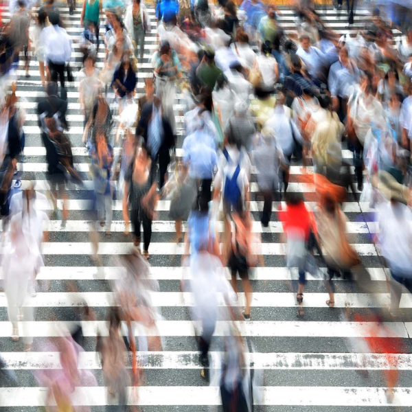 A crowd of people cross a street at a zebra crossing in a blur