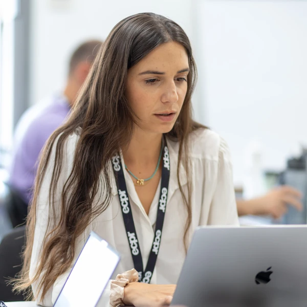 Woman with long brown hair wearing an ECPR branded lanyard seated in front of a laptop during and ECPR course.