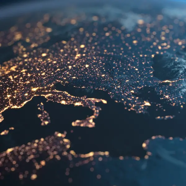 View of Europe and North Africa at night with glowing city lights and clouds swirling over the landmass.