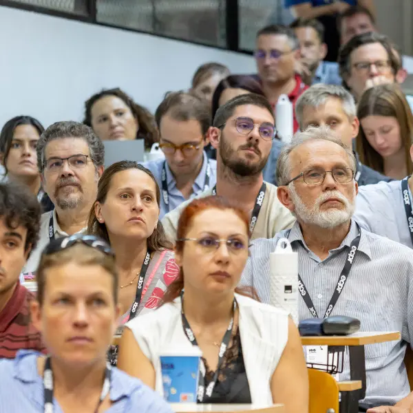 An audience in a lecture at the ECPR conference, attentively looking forward. Several wear ECPR branded lanyards.