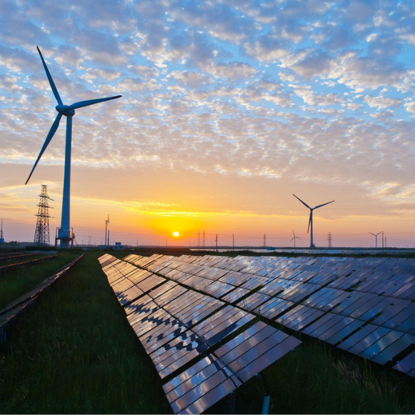 Wind turbines and solar panels at sunset