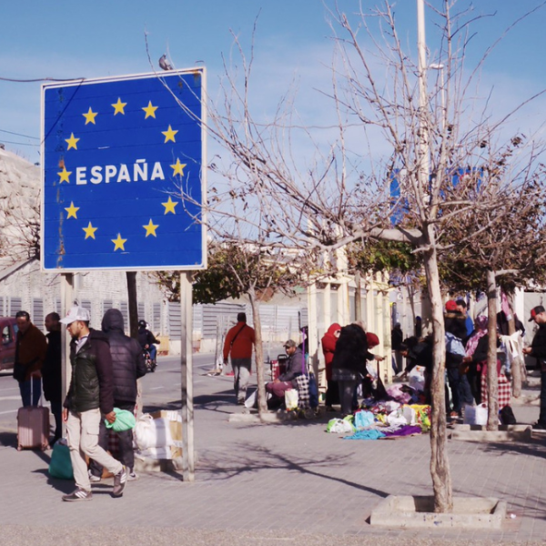 Large blue sign with EU star logo and the word Espana on a street scene with lots of people carrying bags