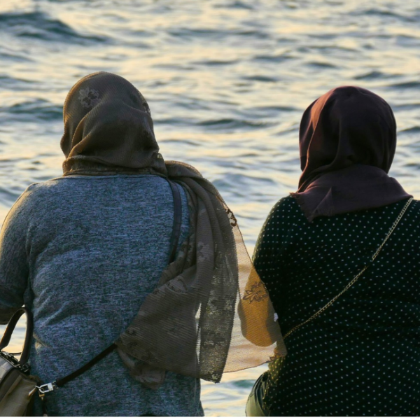Two women wearing hijabs face the sea