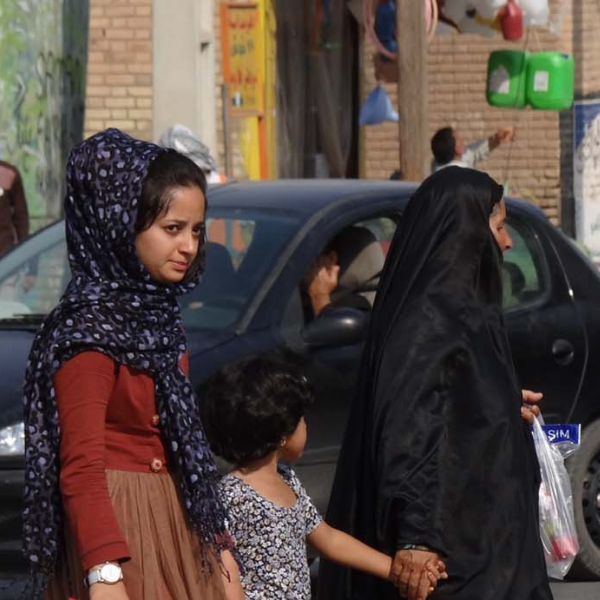 Two women hold hands with a child crossing the road in Iran