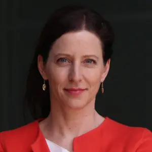 A picture of Silja Häusermann. She has dark hair pulled back, wearing a coral-pink blazer and white shirt, looking directly at the camera with a neutral expression.